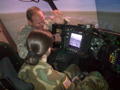 C/MSgt Abigail Ham flies an Apache helicopter simulation with assistance from Army Air Guard Chief Warrant Officer Chris Wilson on Dec. 29, 2014.