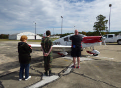 C/Amn Travis Jackson waits as parents of Young Eagles take photos before pilot Gary Hodges takes off with their children.